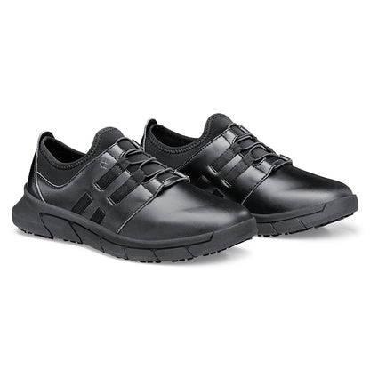 The Karina Black by Lila from Shoes For Crews are black slip-resistant trainers that are lightweight and have Flex Tread technology, pair seen in profile on the right.