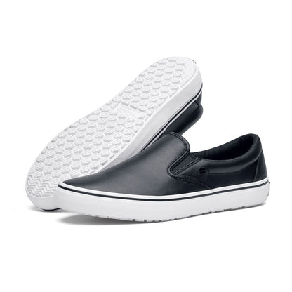 The Merlin Slip On Black and White from Shoes For Crews are slip-on trainers that are slip-resistant, lightweight, easy to clean and water-resistant, pair seen from the left side and the sole.